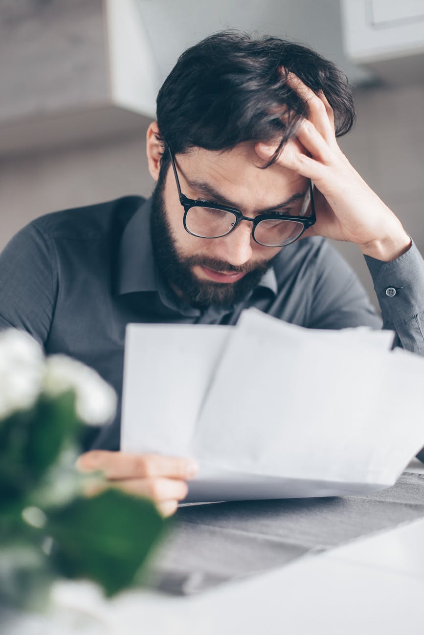 stressed man holding head while reviewing documents