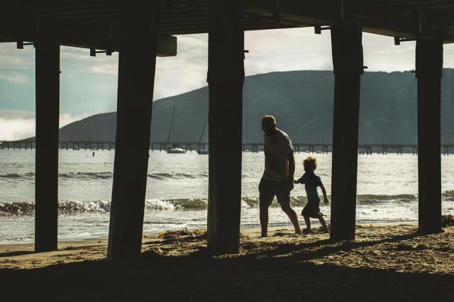 man walking with child on beach